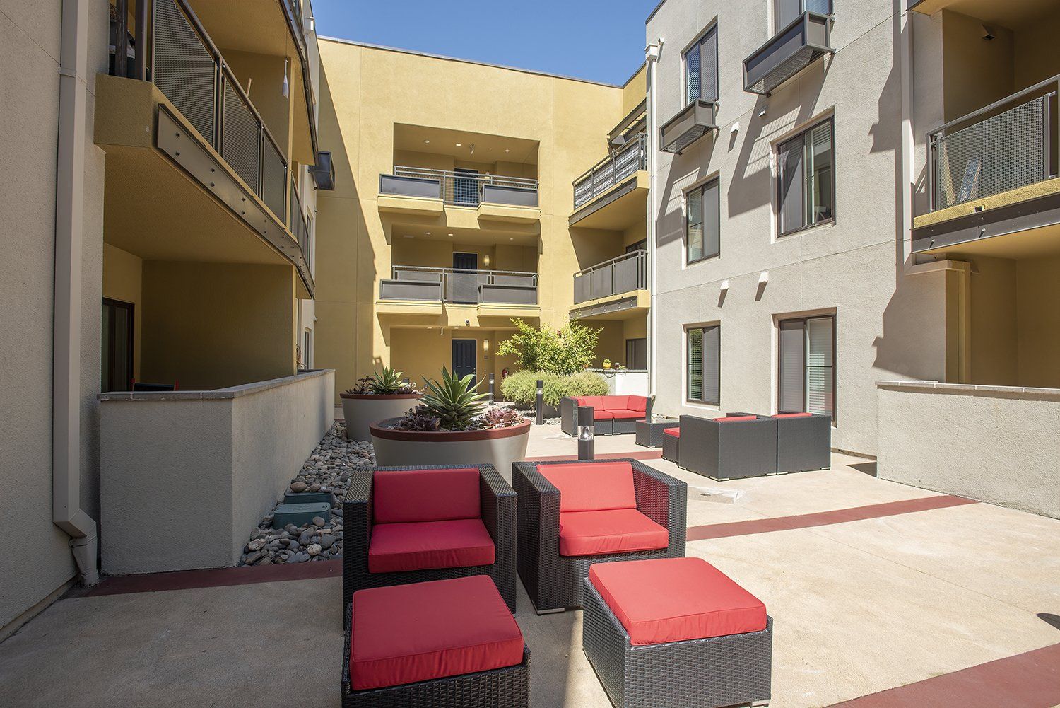 El Cerrito Apartments - Metro 510 - Courtyard In The Heart Of The Complex. The Courtyard Has Plush Seating, Stools, Lights, Potted Plants, And Maintained Landscaping.