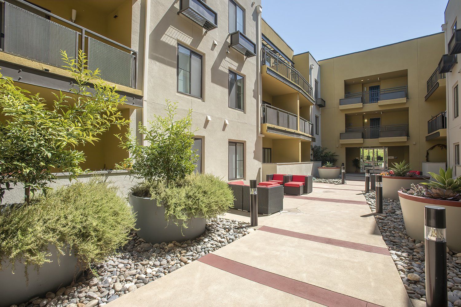 El Cerrito Apartments - Metro 510 - Courtyard In The Heart Of The Complex. The Courtyard Has Plush Seating, Stools, Lights, Potted Plants, And Maintained Landscaping.