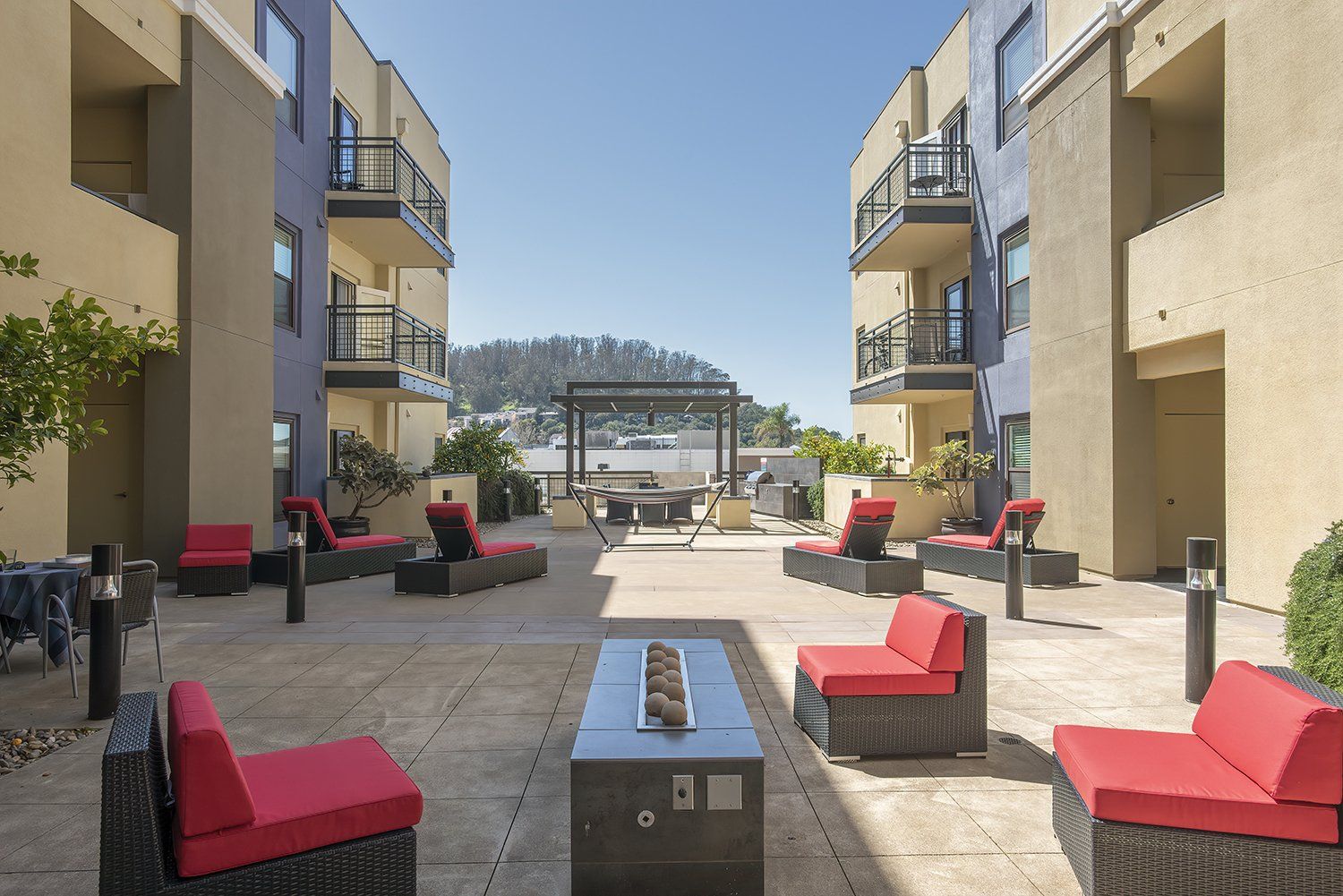 Luxury Apartments for Rent in El Cerrito CA - Metro 510 - outdoor Courtyard In The Heart Of The Complex, with Red Plush Seats, Stools, Lights, Potted Plants, and Maintained Landscaping