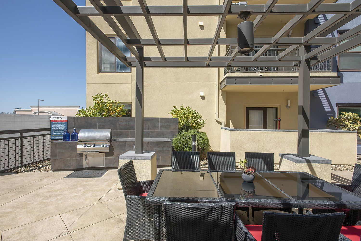 El Cerrito, CA Apartments - Metro 510 - BBQ Grill Area With A Table, Chairs, Gas BBQ Grill, And Maintained Landscaping.