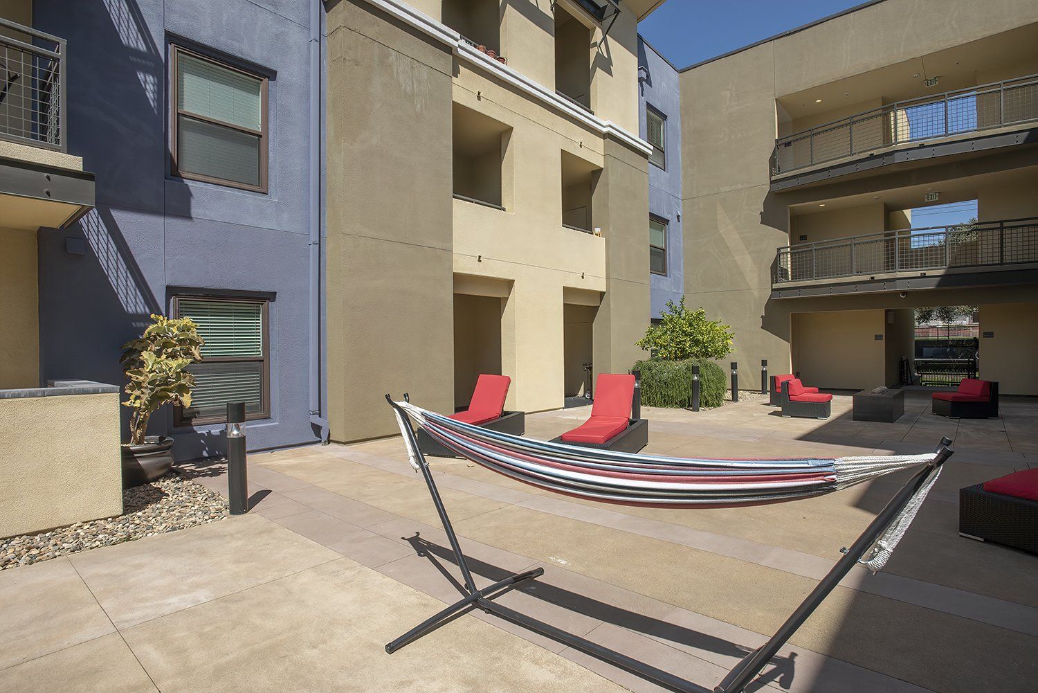 El Cerrito Apartments - Metro 510 - Courtyard In The Heart Of The Complex. The Courtyard Has Plush Seating, Stools, Lights, Potted Plants, And Maintained Landscaping.