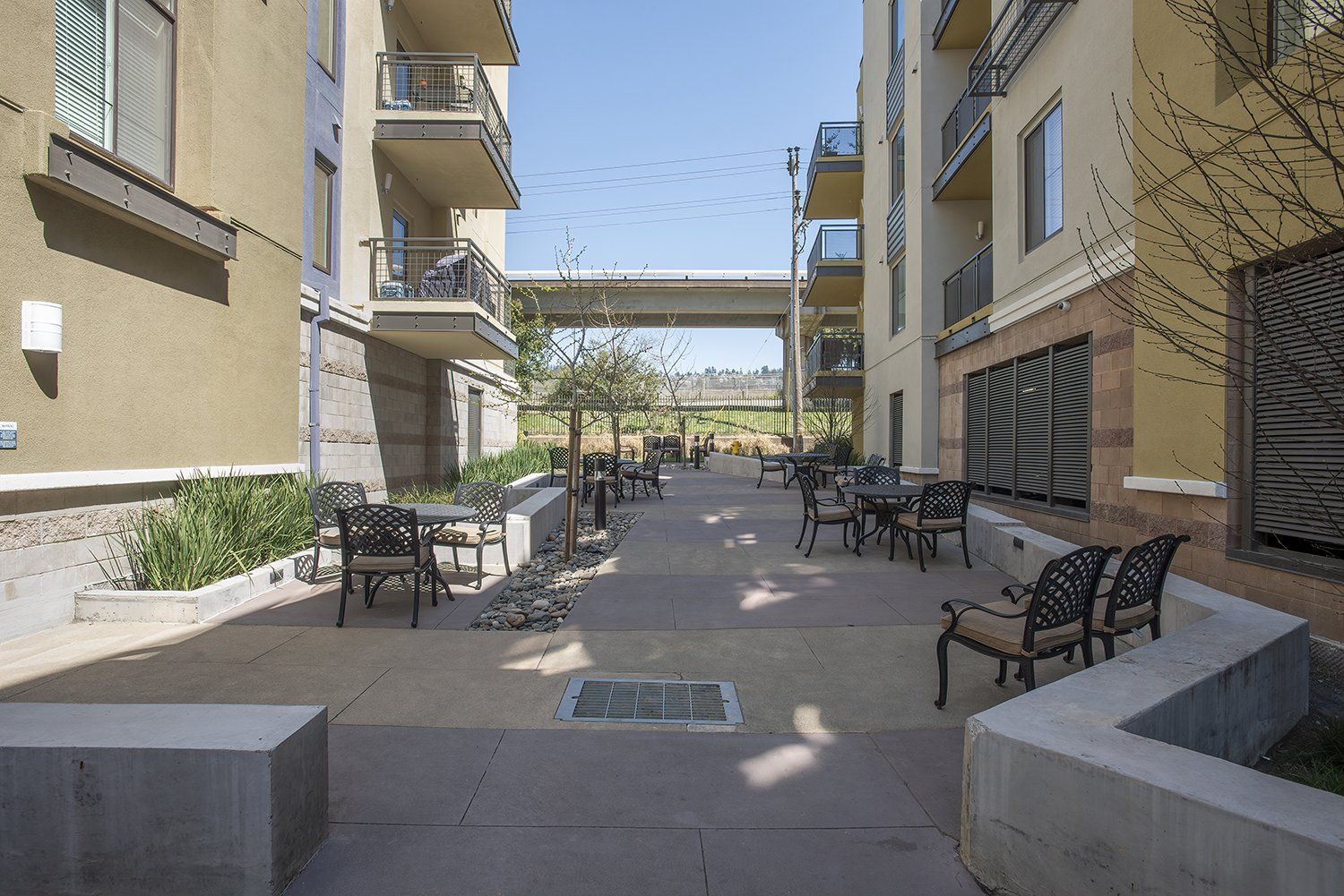 El Cerrito Apartments - Metro 510 - Courtyard In The Heart Of The Complex. The Courtyard Has Plush Seating, Stools, Lights, Potted Plants, And Maintained Landscaping.