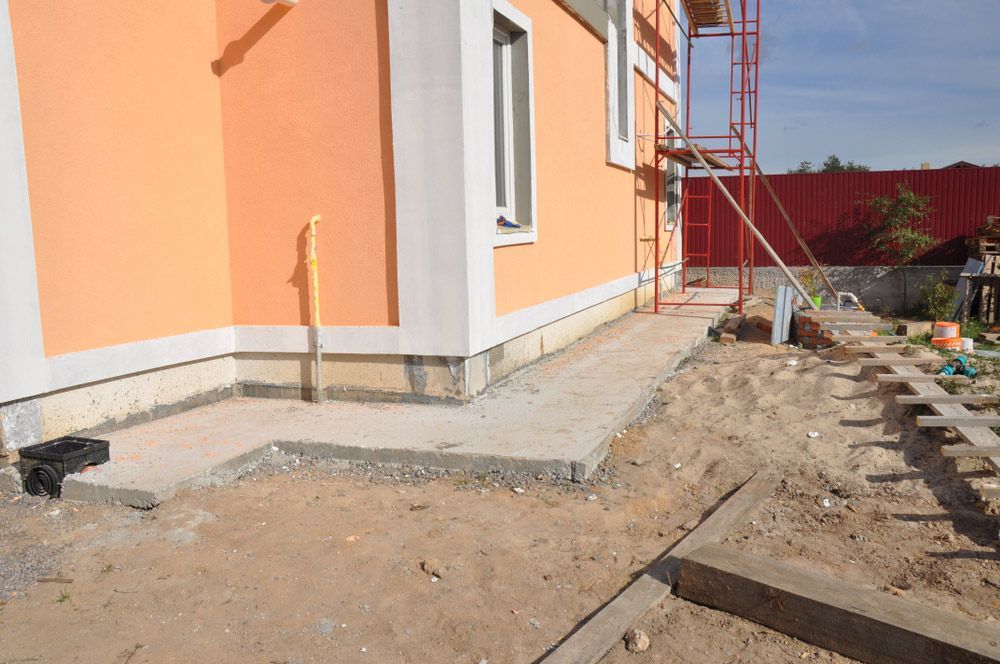 A Concrete Walkway is Being Built in Front of a House Under Construction — Tony Eldridge Property Services in Forster, NSW