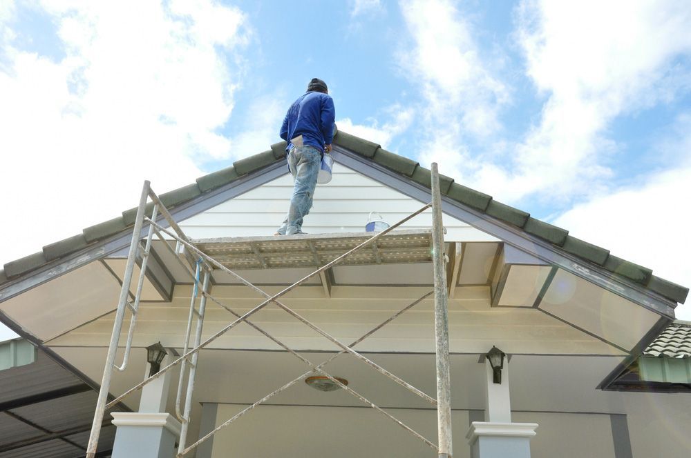 A Man is Standing on a Scaffolding on Top of a House — Tony Eldridge Property Services in Forster, NSW