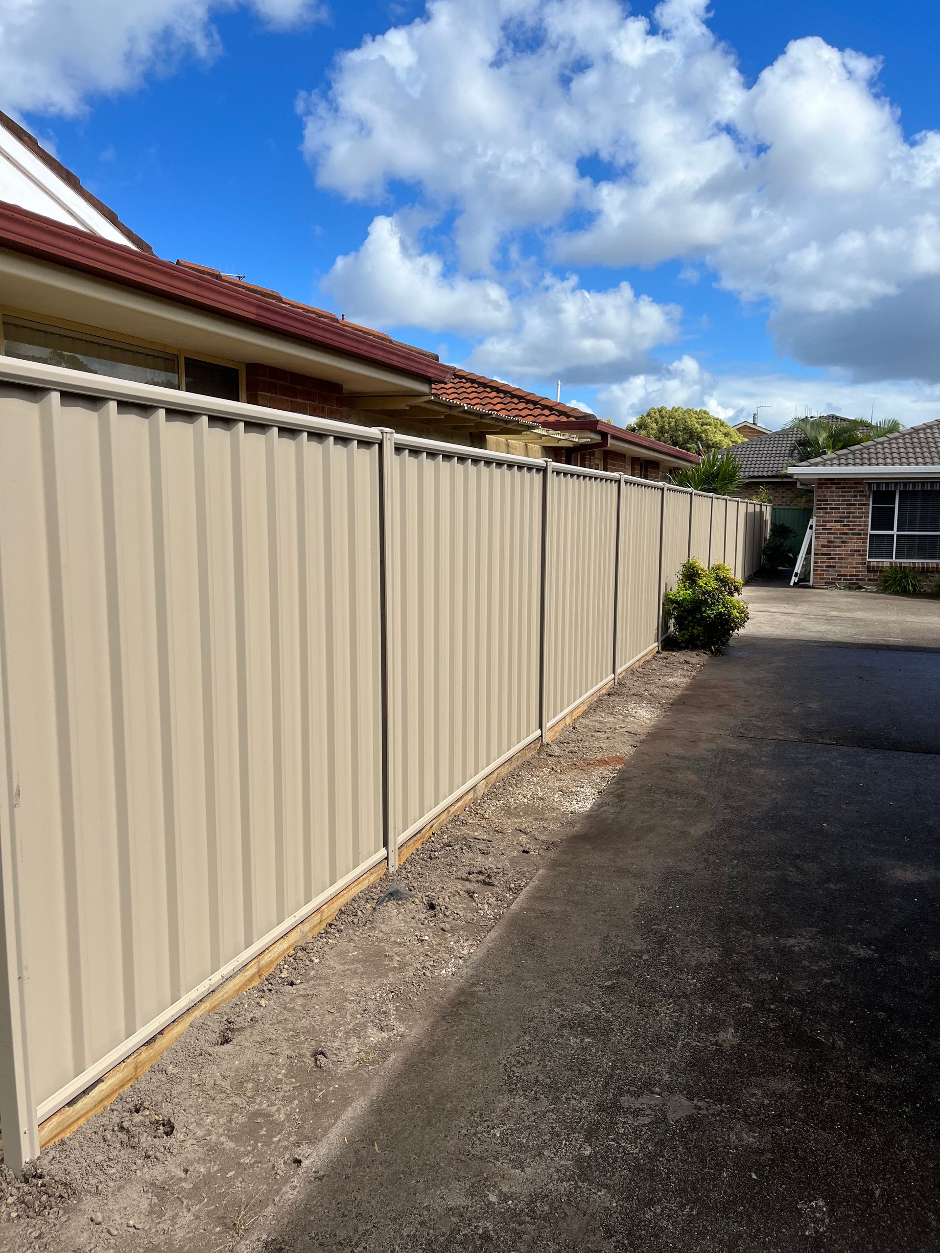 Tan corrugated metal fence along a driveway — Tony Eldridge Property Services in Forster, NSW