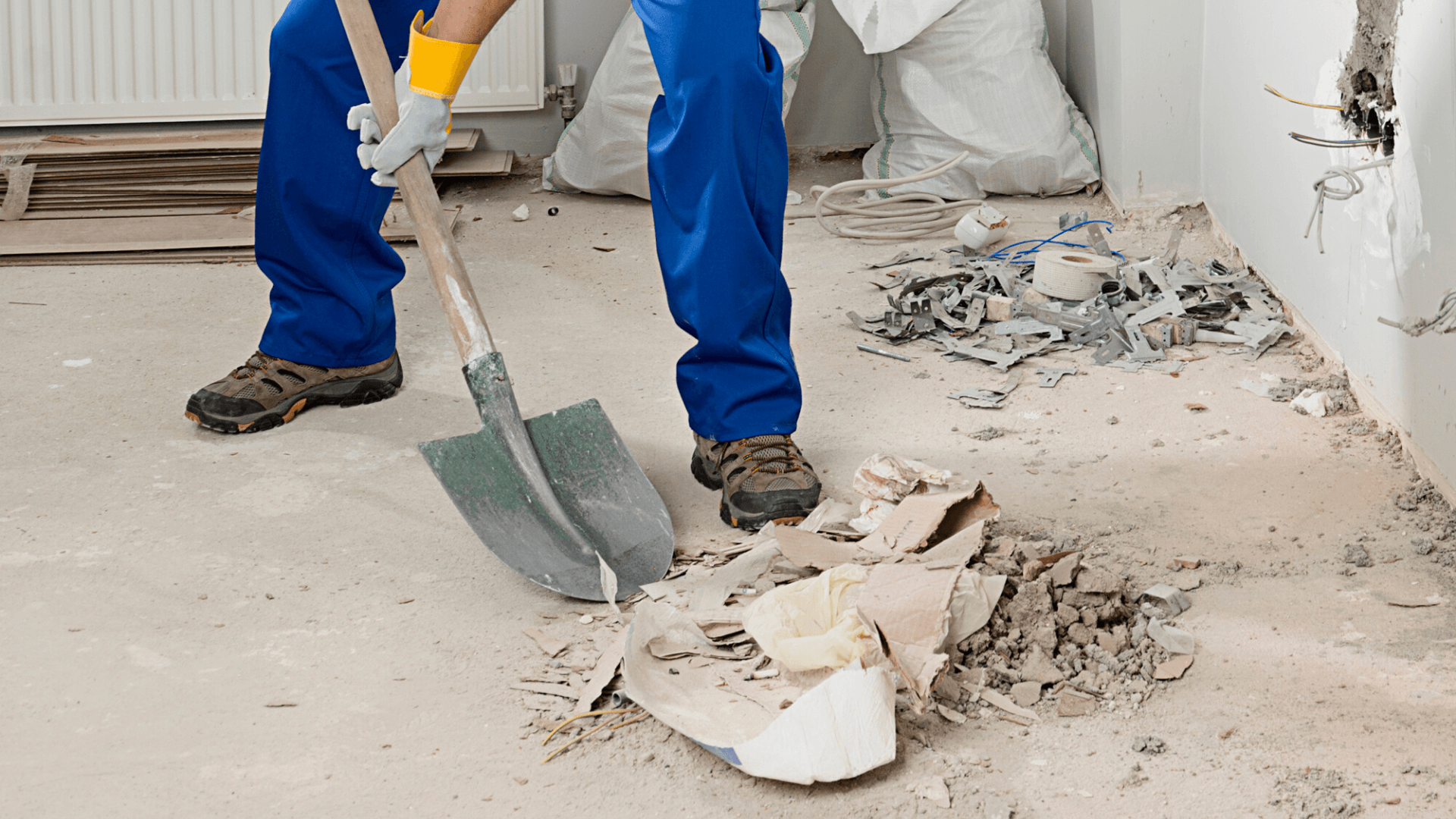 Man cleaning piles of debris, scattered dirt, and discarded materials after construction.