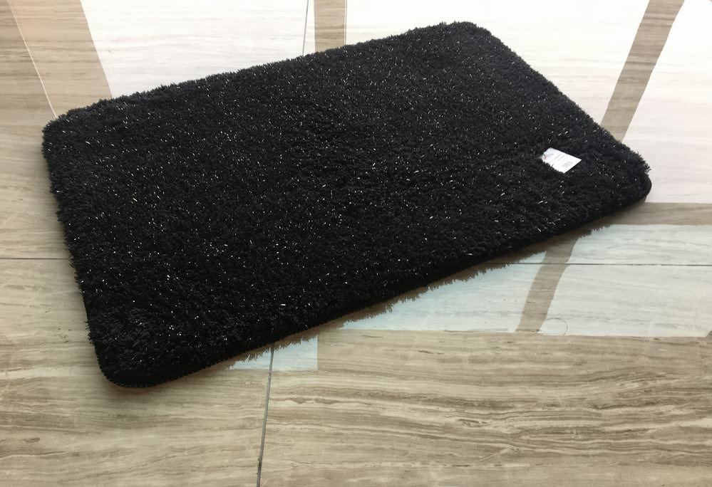 A black rug is laying on a wooden floor