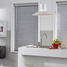 A kitchen with a sink and a bowl of apples on the counter.