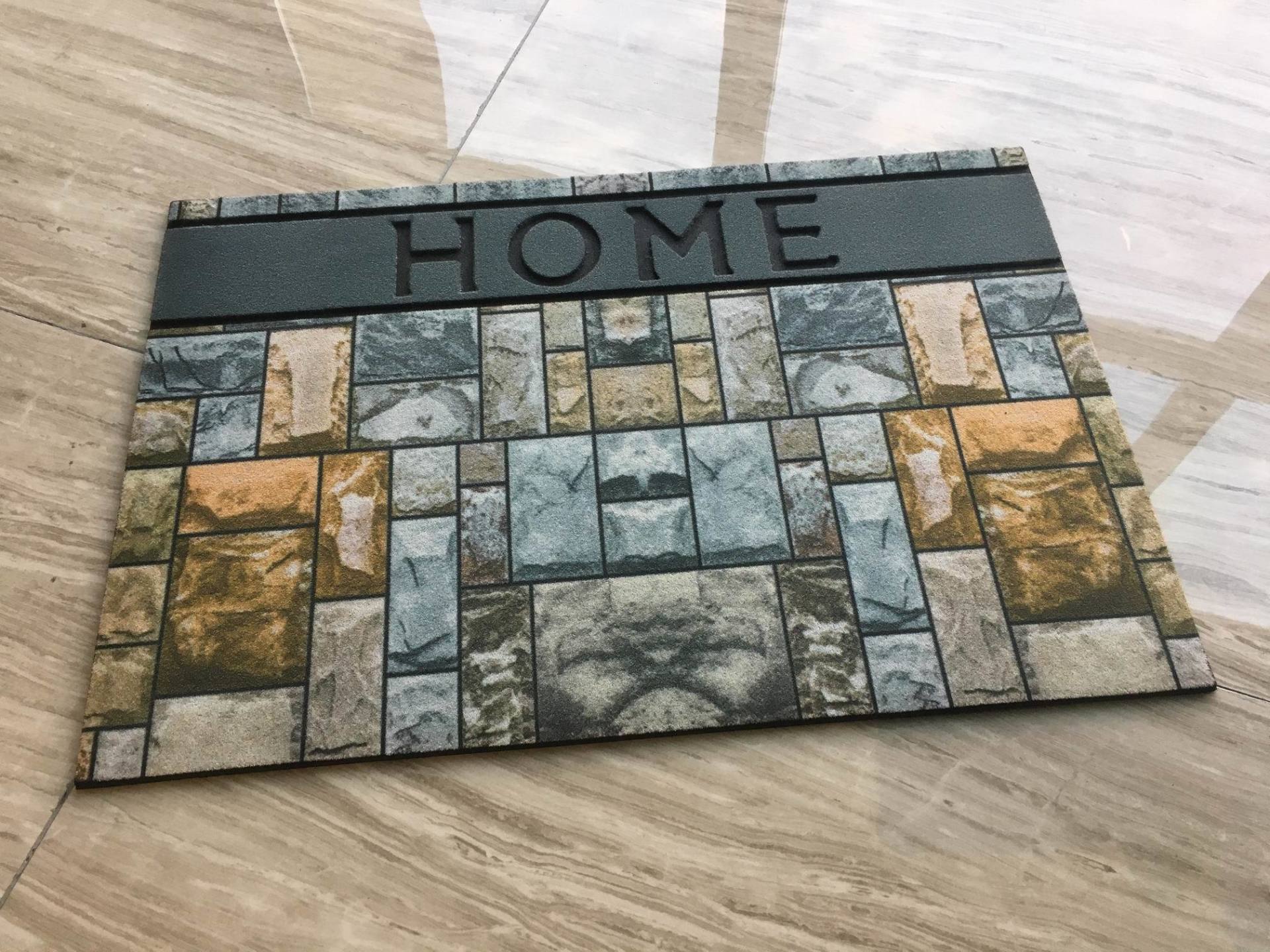 A door mat with the word home on it is sitting on a wooden floor.