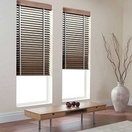 A living room with two windows , a table , and a vase.