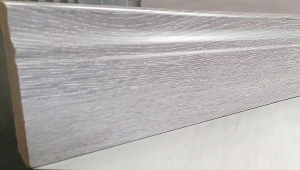 A white wooden skirting board is sitting on a white surface.