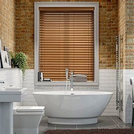 A bathroom with a tub , toilet , sink and window with wooden blinds.
