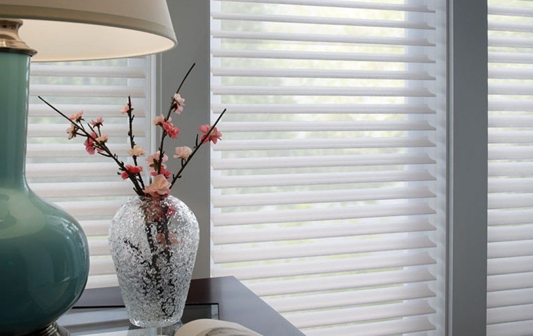 A vase of flowers is sitting on a table next to a lamp.