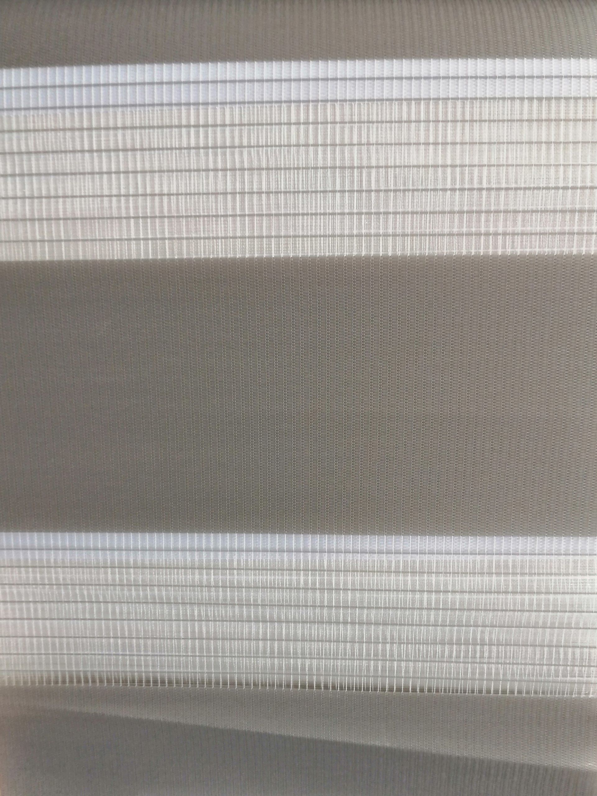 A close up of a gray and white striped blind on a window.