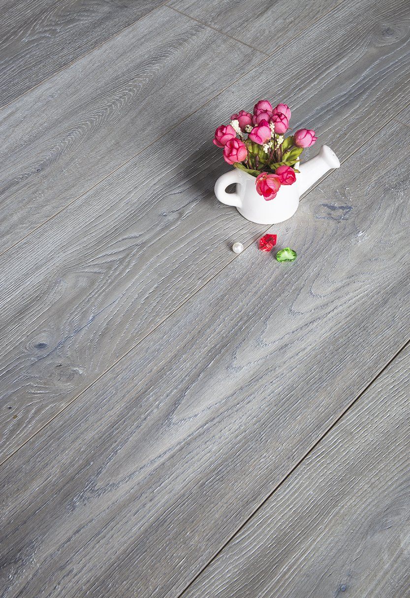 A vase of flowers is sitting on a wooden floor.