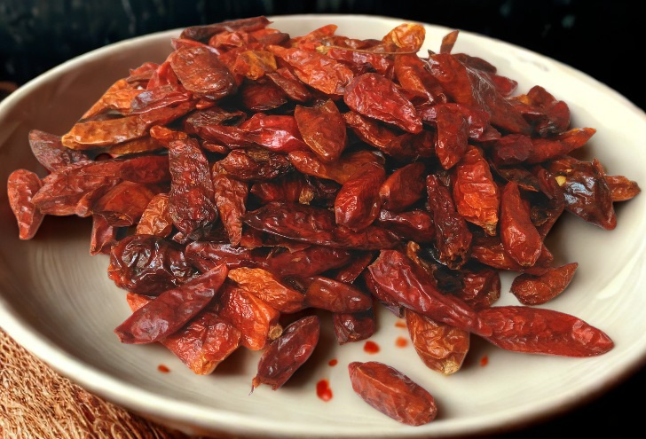 Dried red chilies piled in a white bowl.