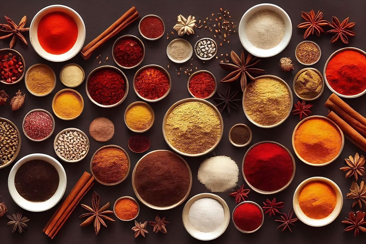 Overhead shot of bowls of colorful spices and seasonings, with cinnamon sticks and star anise.