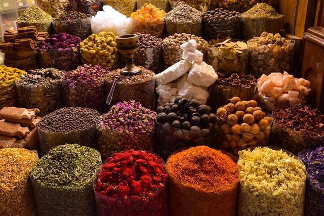 Bags of colorful spices on display at a market, including reds, oranges, greens, and purples.