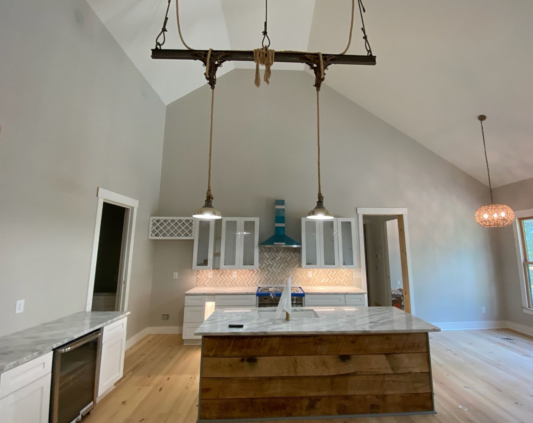 Kitchen with white cabinets, a wooden island, and unique hanging light fixtures.