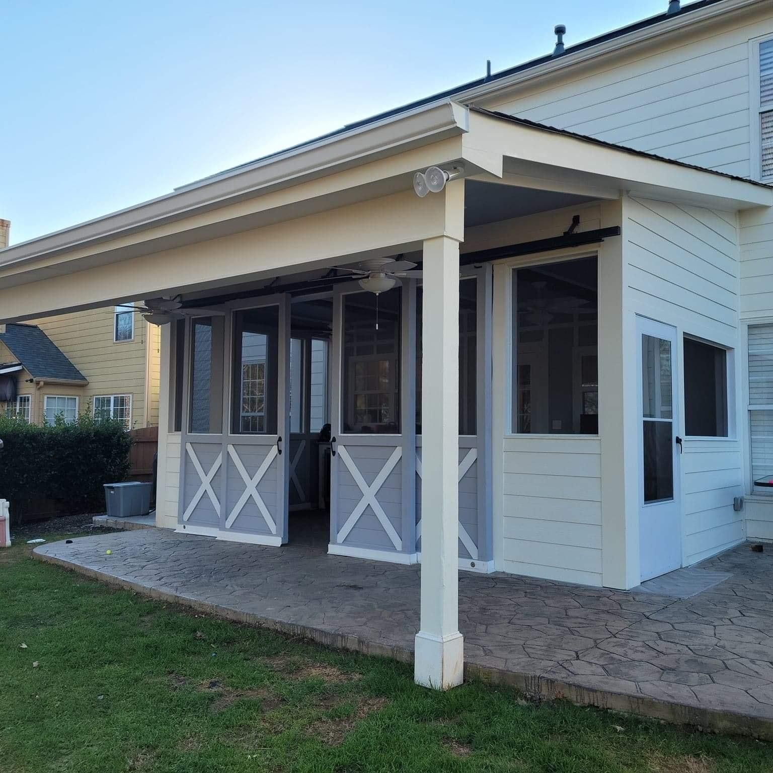 Screened-in porch with white walls, gray doors, and a concrete patio, attached to a two-story house.