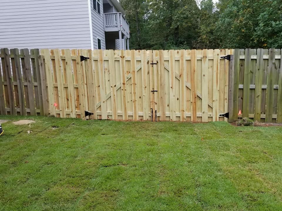Wooden fence with a gate in a grassy yard.