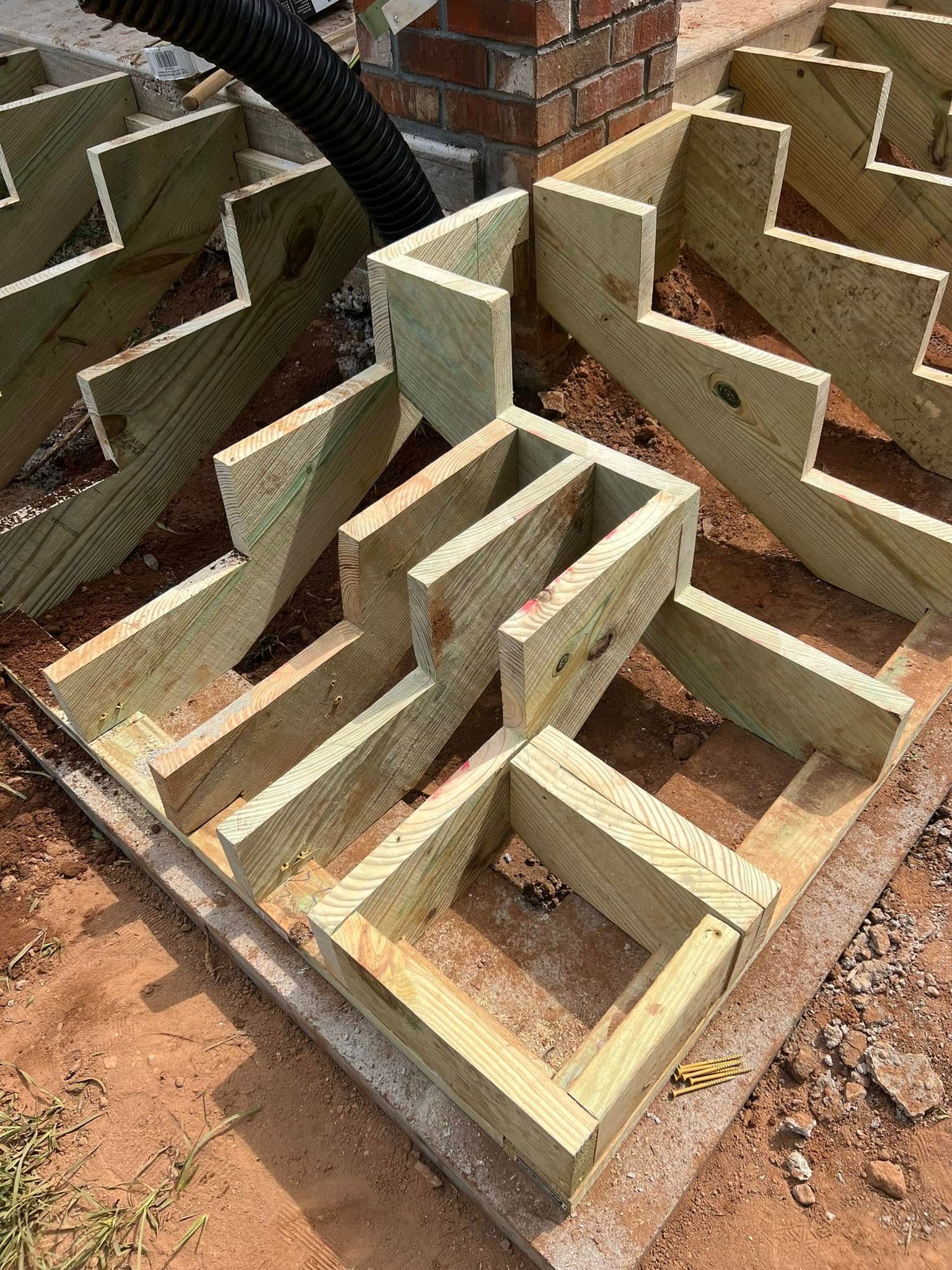 Wooden deck framing being constructed outdoors on a gravel base.