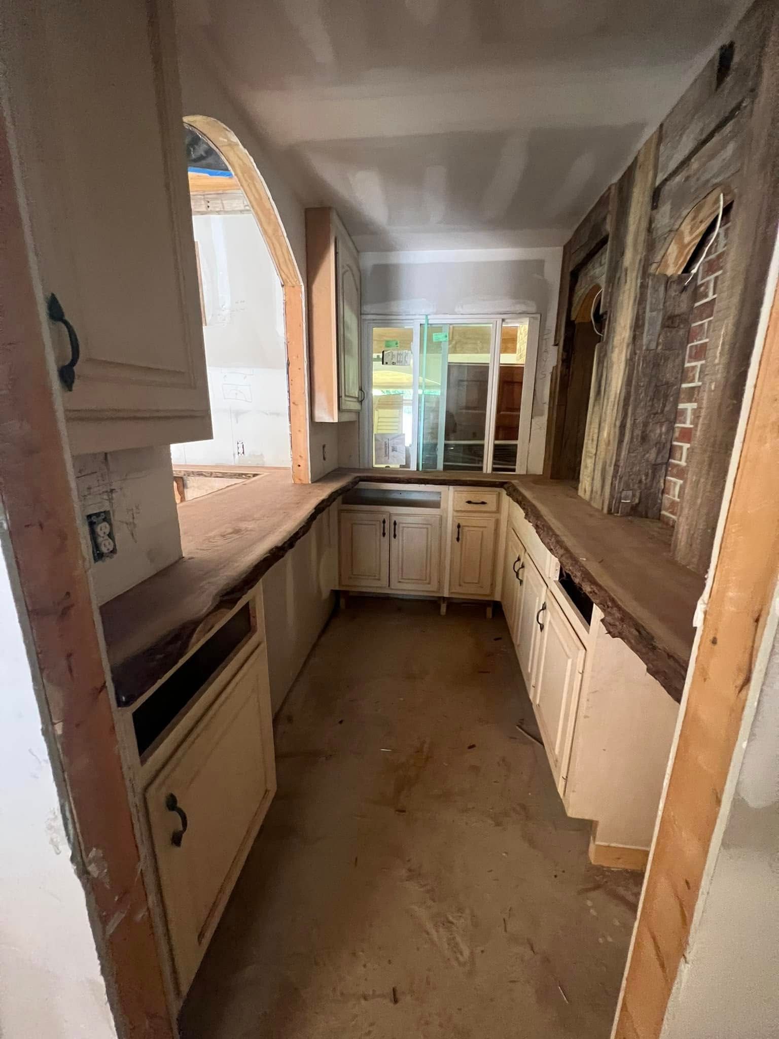 Kitchen undergoing renovation with cabinets, counters, and a window in the center.