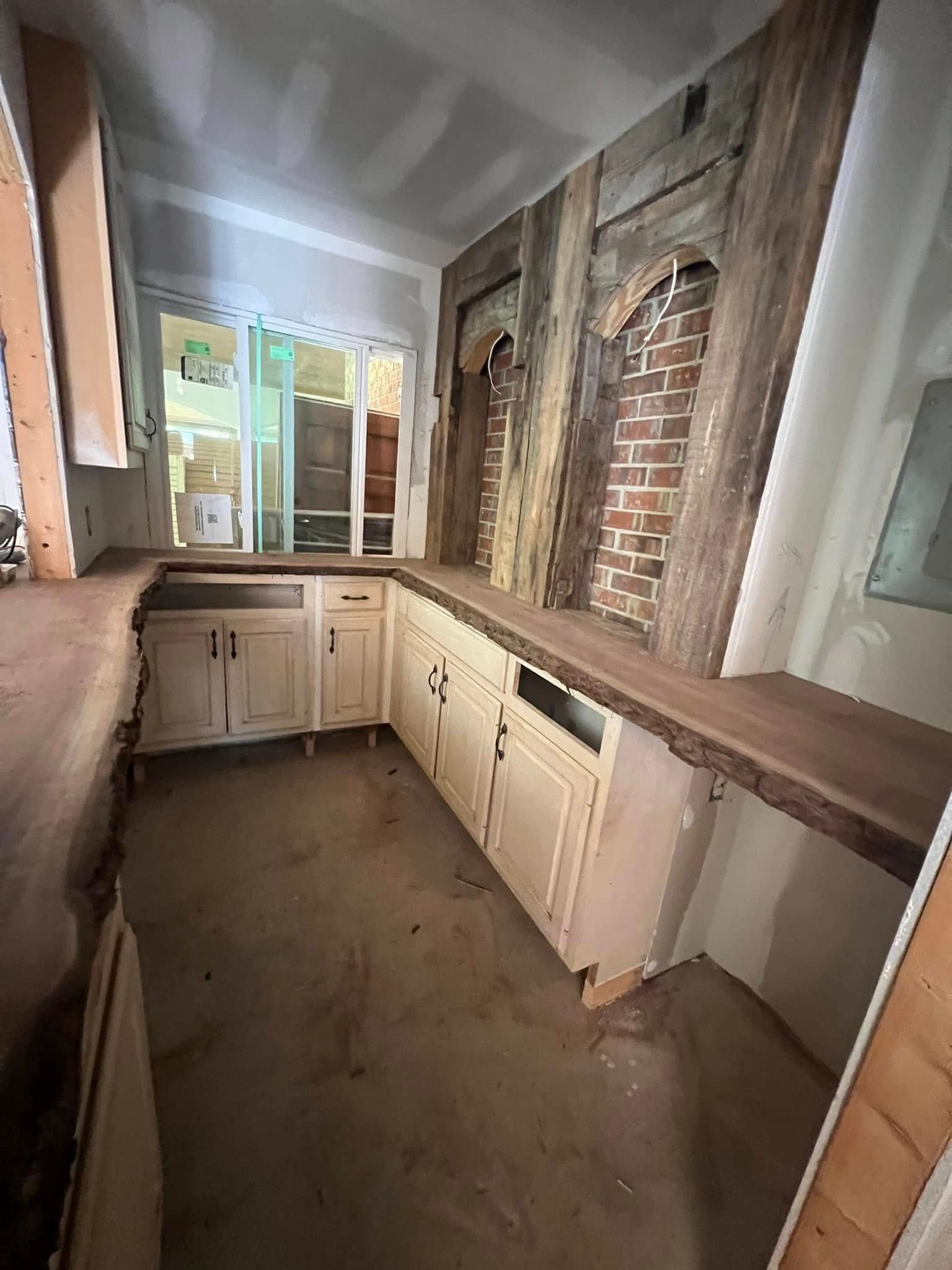 Kitchen with cream cabinets, dark wood countertop, exposed brick, and wooden beam accents.