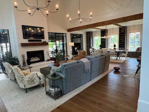 Spacious living room with fireplace, couches, wood floor, and large windows.
