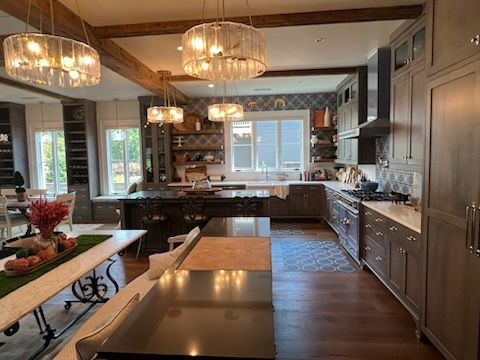 Spacious kitchen with dark island, gray cabinets, and three crystal chandeliers.
