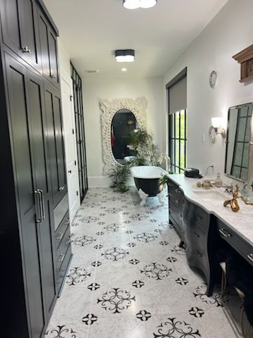 Long bathroom with patterned floor, dark cabinetry, and a clawfoot tub.