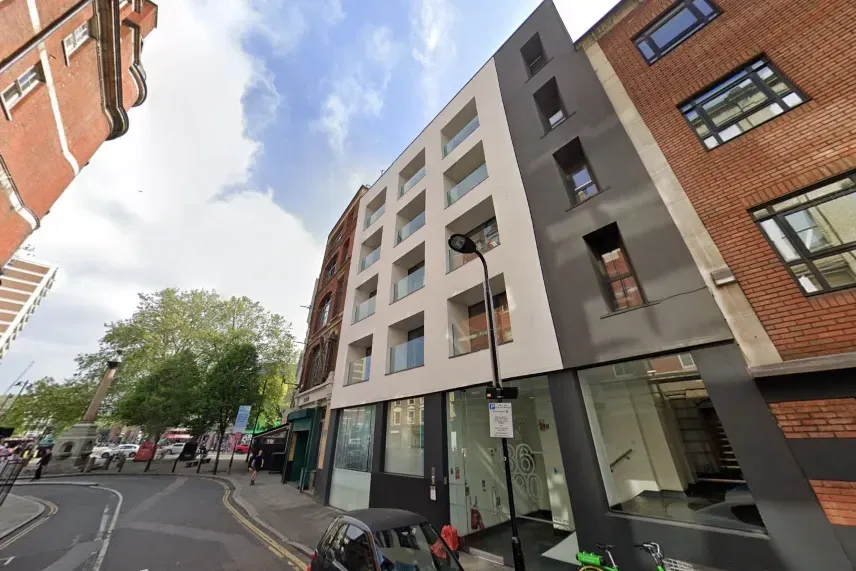 Building exterior: modern white and dark gray facade, several floors, street view.