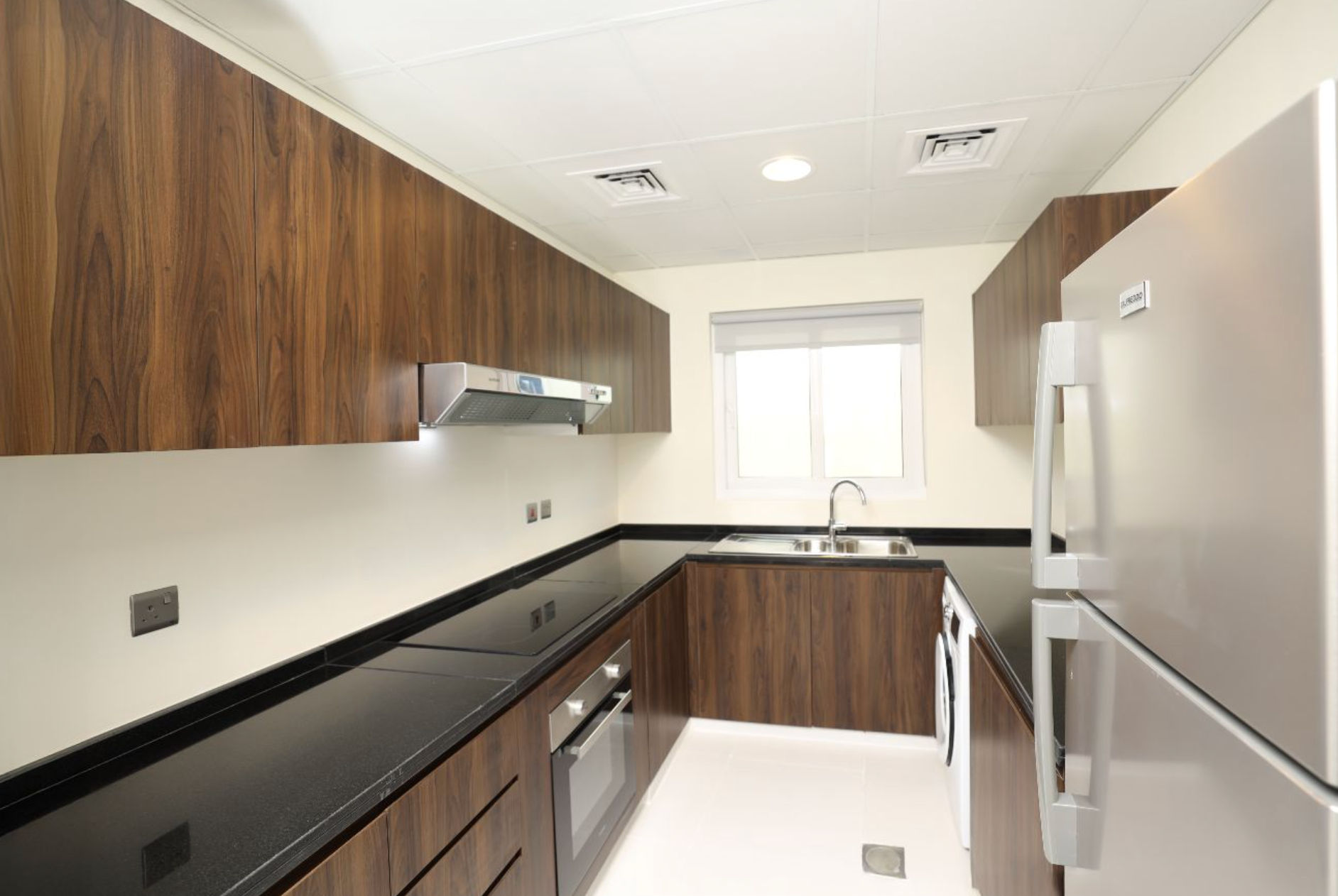 U-shaped kitchen with dark wood cabinets, black countertop, stainless steel appliances, and a small window.