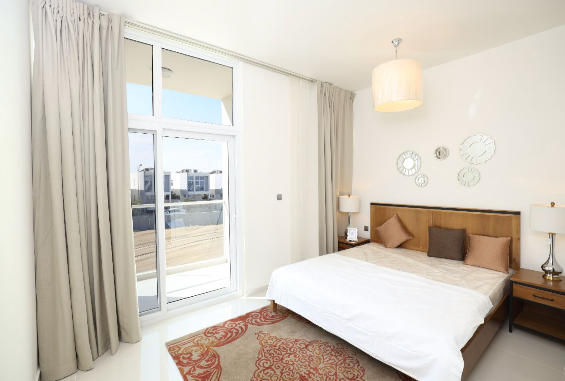 Bedroom with a bed, large window, rug, and neutral color palette.