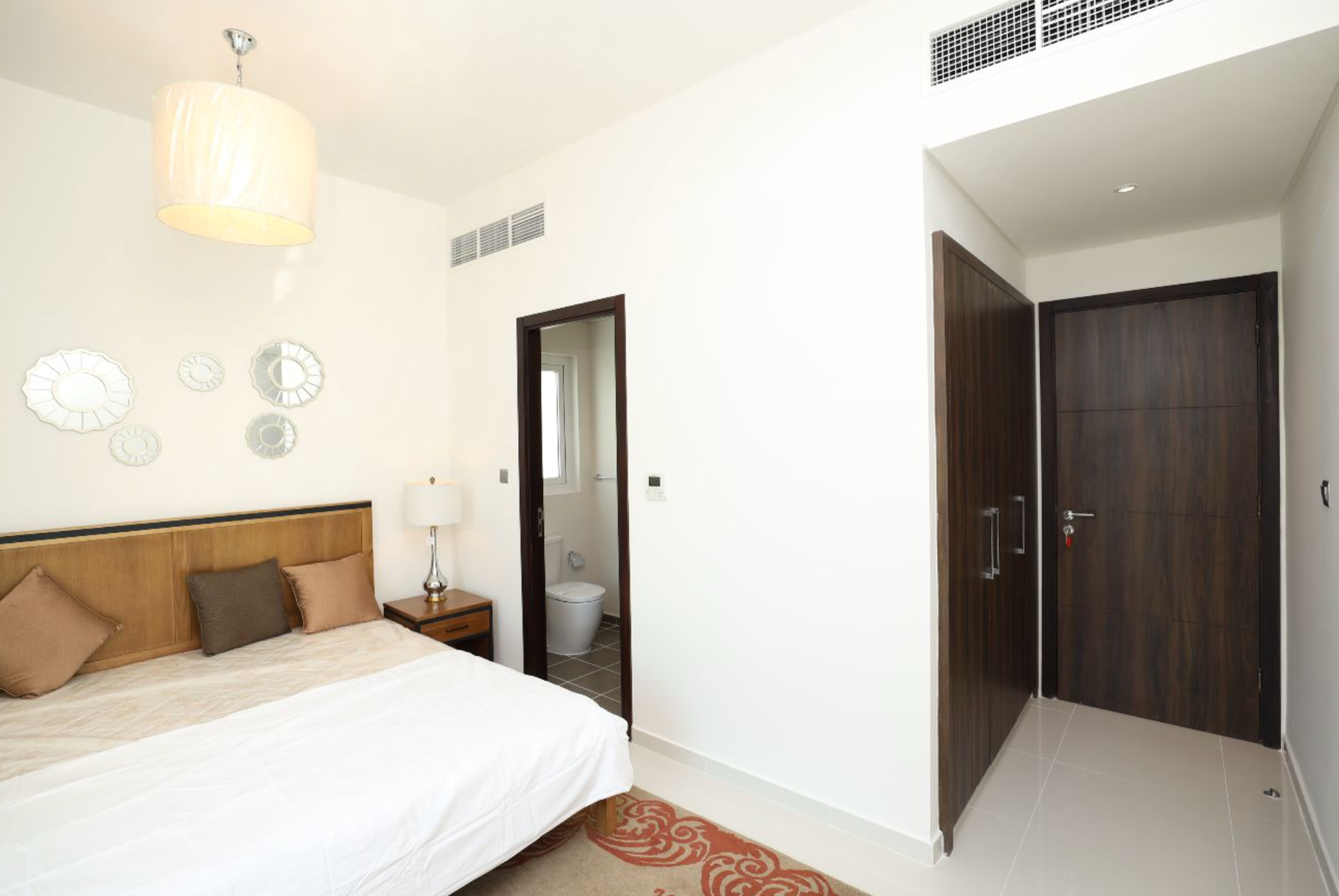 Bedroom interior with bed, bedside table, closet, and open doorway to a bathroom.