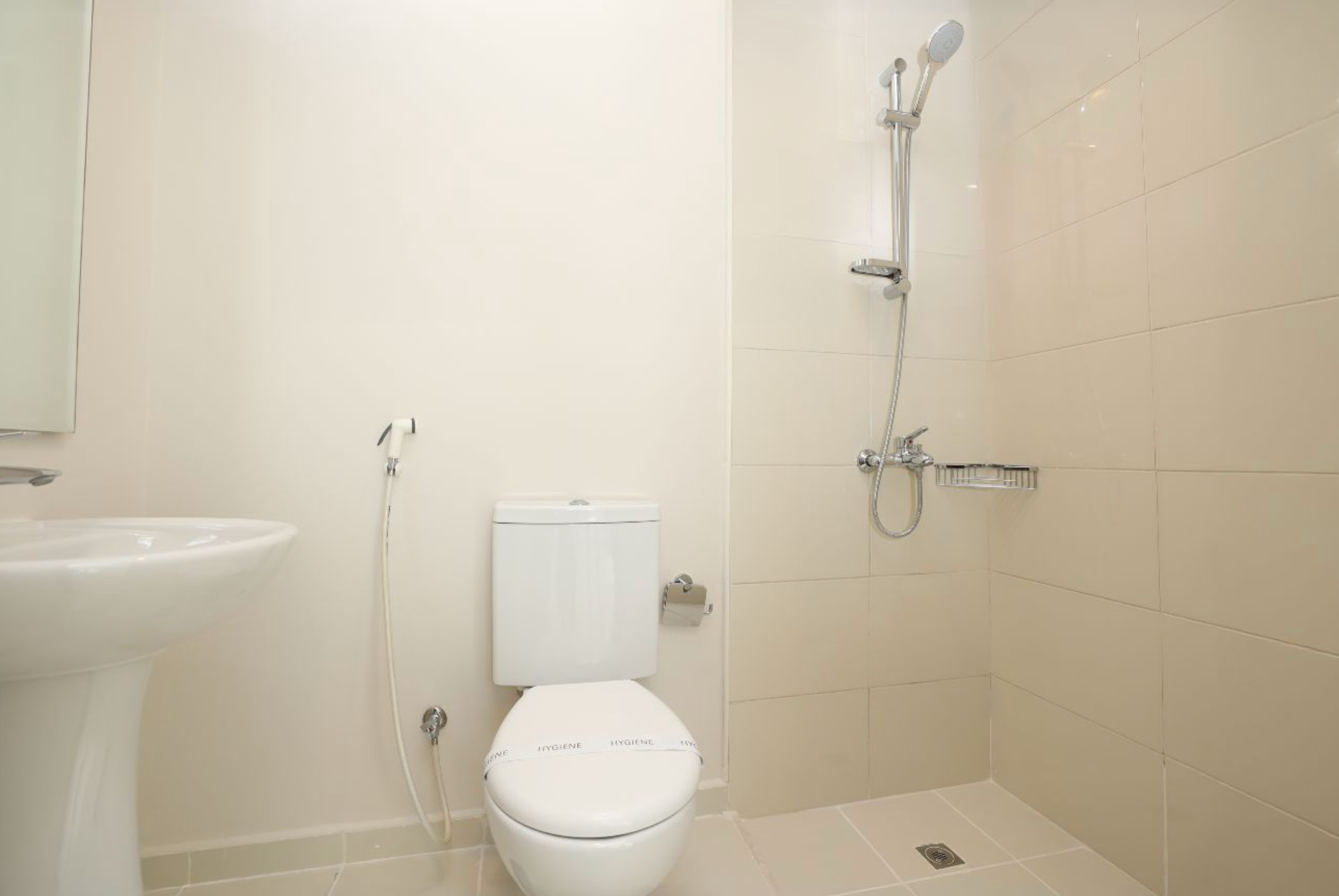 Bathroom with a white toilet, pedestal sink, and shower with silver fixtures.