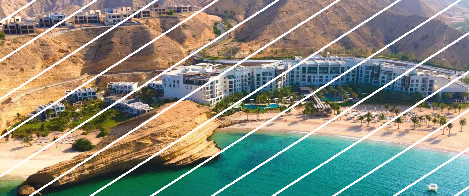 Coastal resort with beach, turquoise water, mountains.