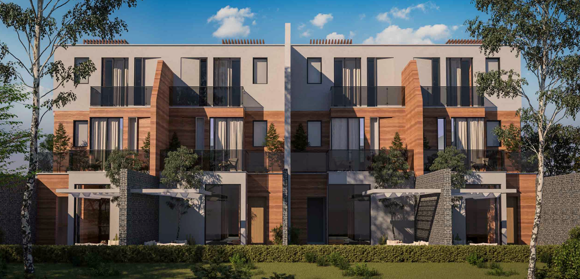 Modern townhouses with brick and gray siding, balconies, and trees under a blue sky.