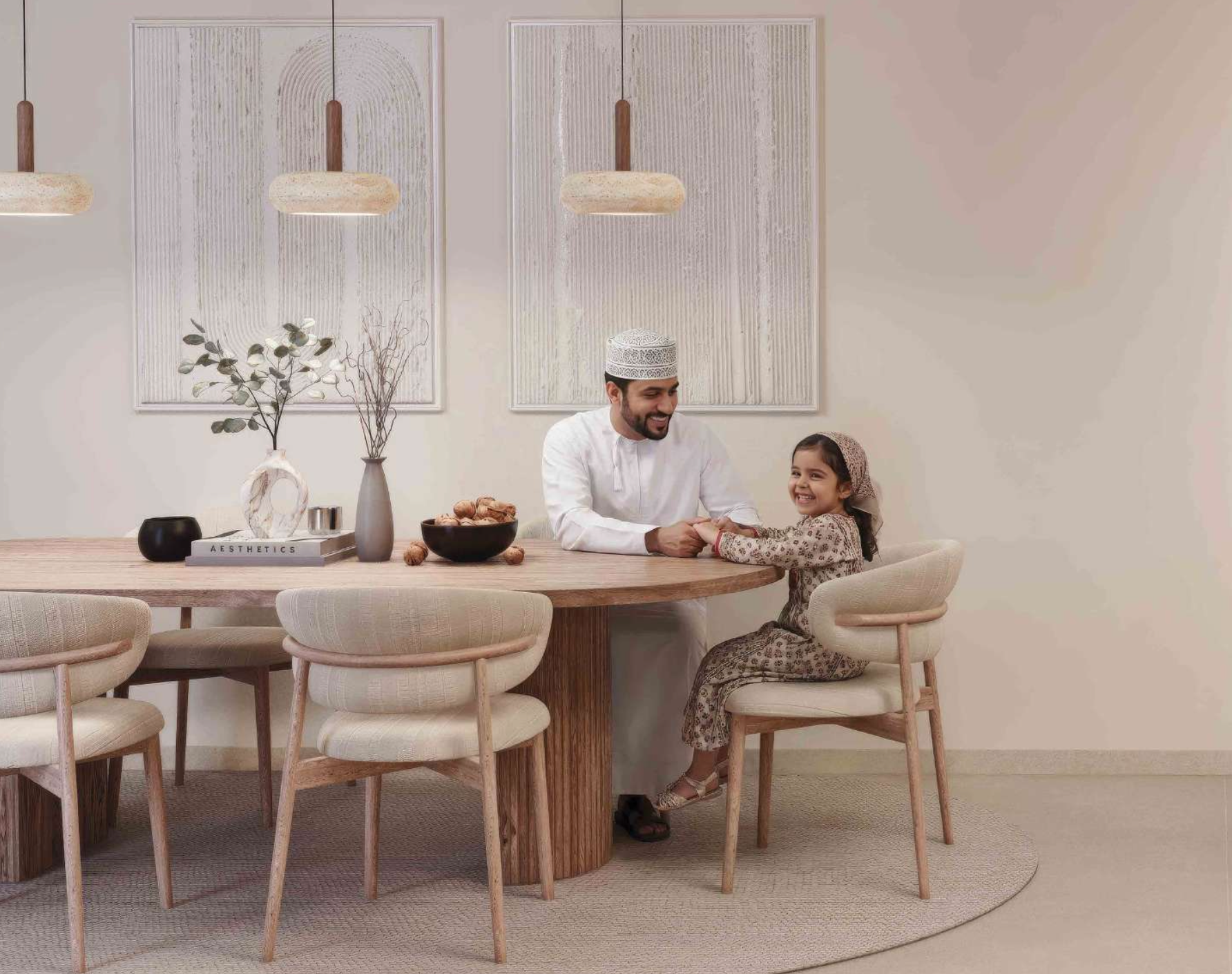 A man and a child sitting at a dining table, possibly at home. The setting is bright and the furniture is modern.