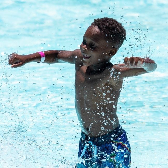 A young boy is splashing in a swimming pool.