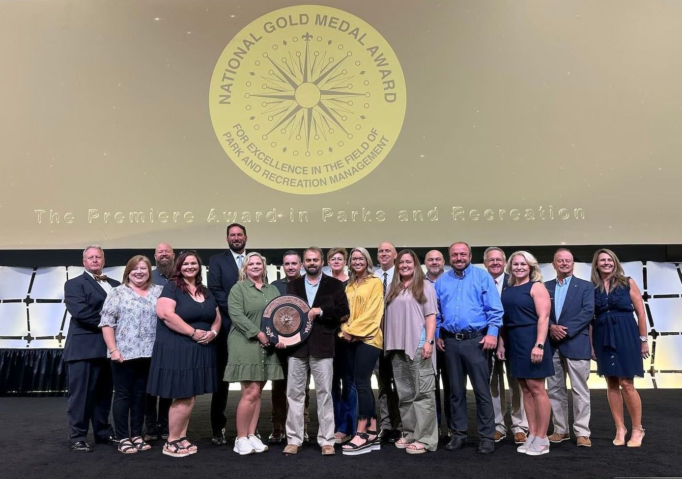 A group of people standing in front of a sign that says national gold medal award