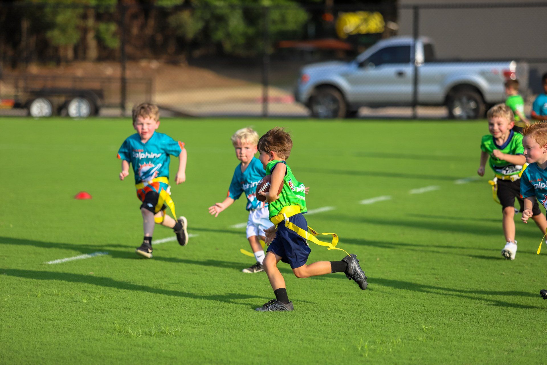 A group of young boys are playing flag football on a field.