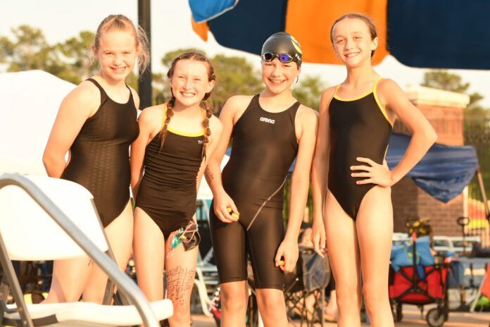 A group of young girls in swimsuits are posing for a picture