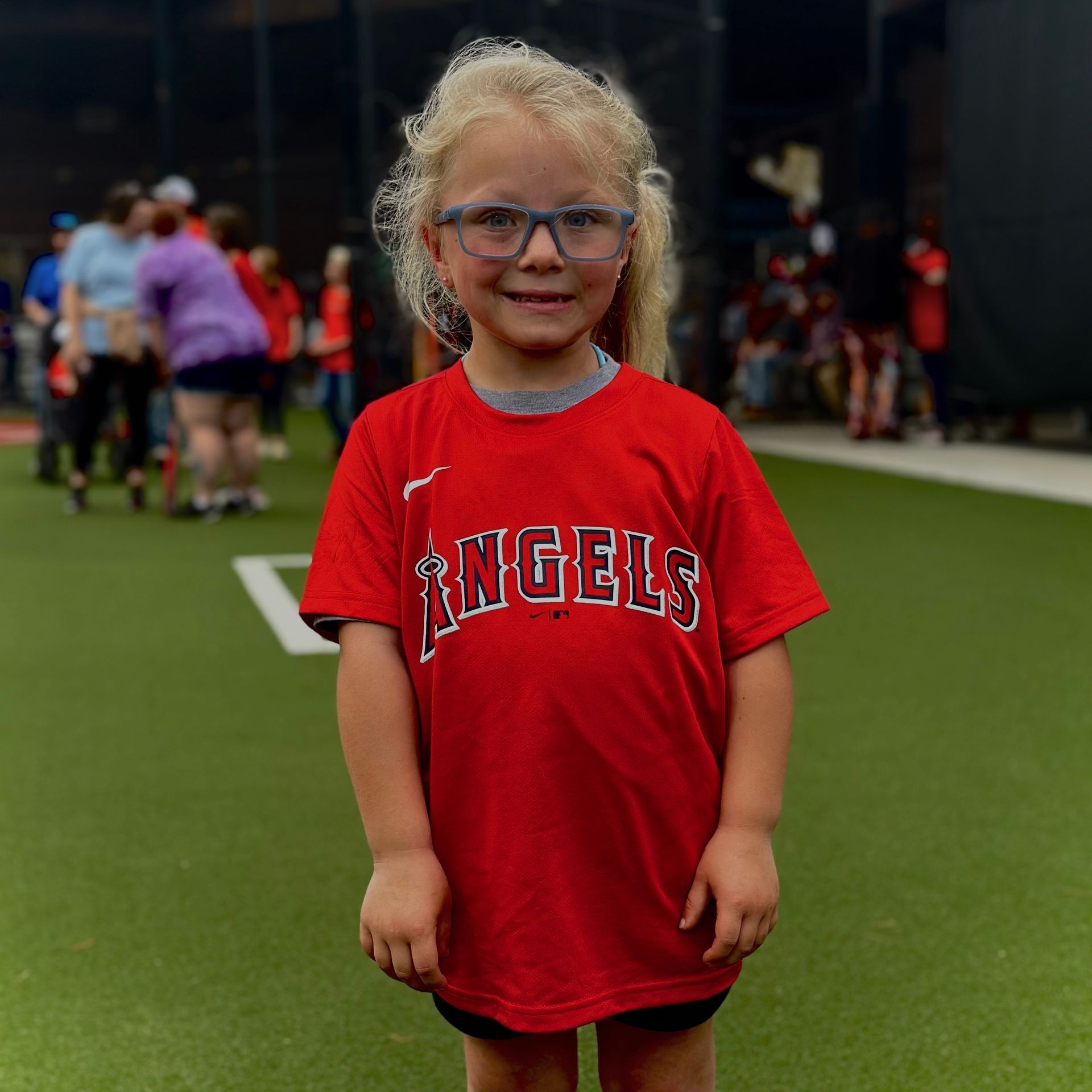 A little girl wearing a red shirt that says angels