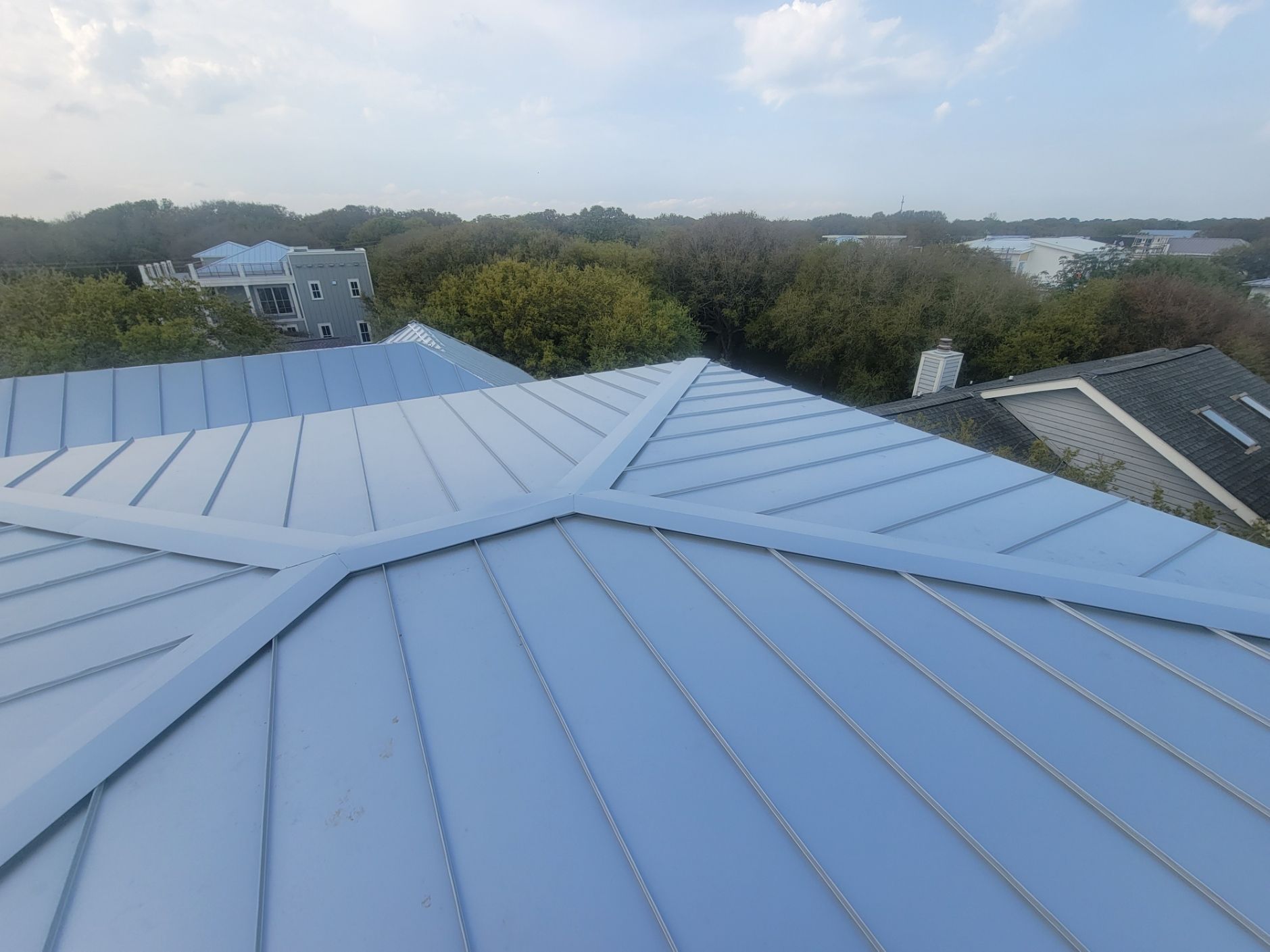 The roof of a building with a blue roof and trees in the background