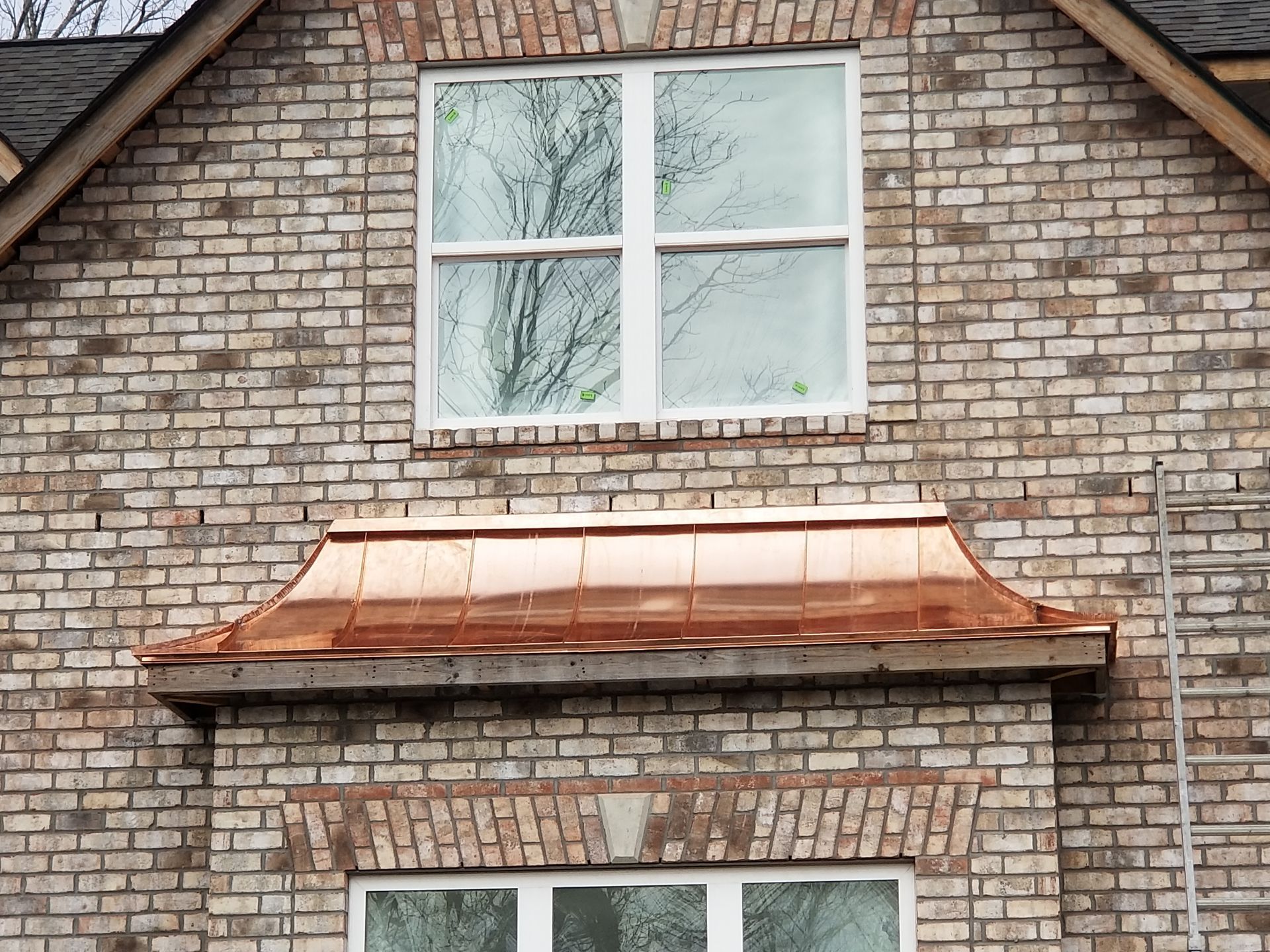 A brick building with a window and a copper roof