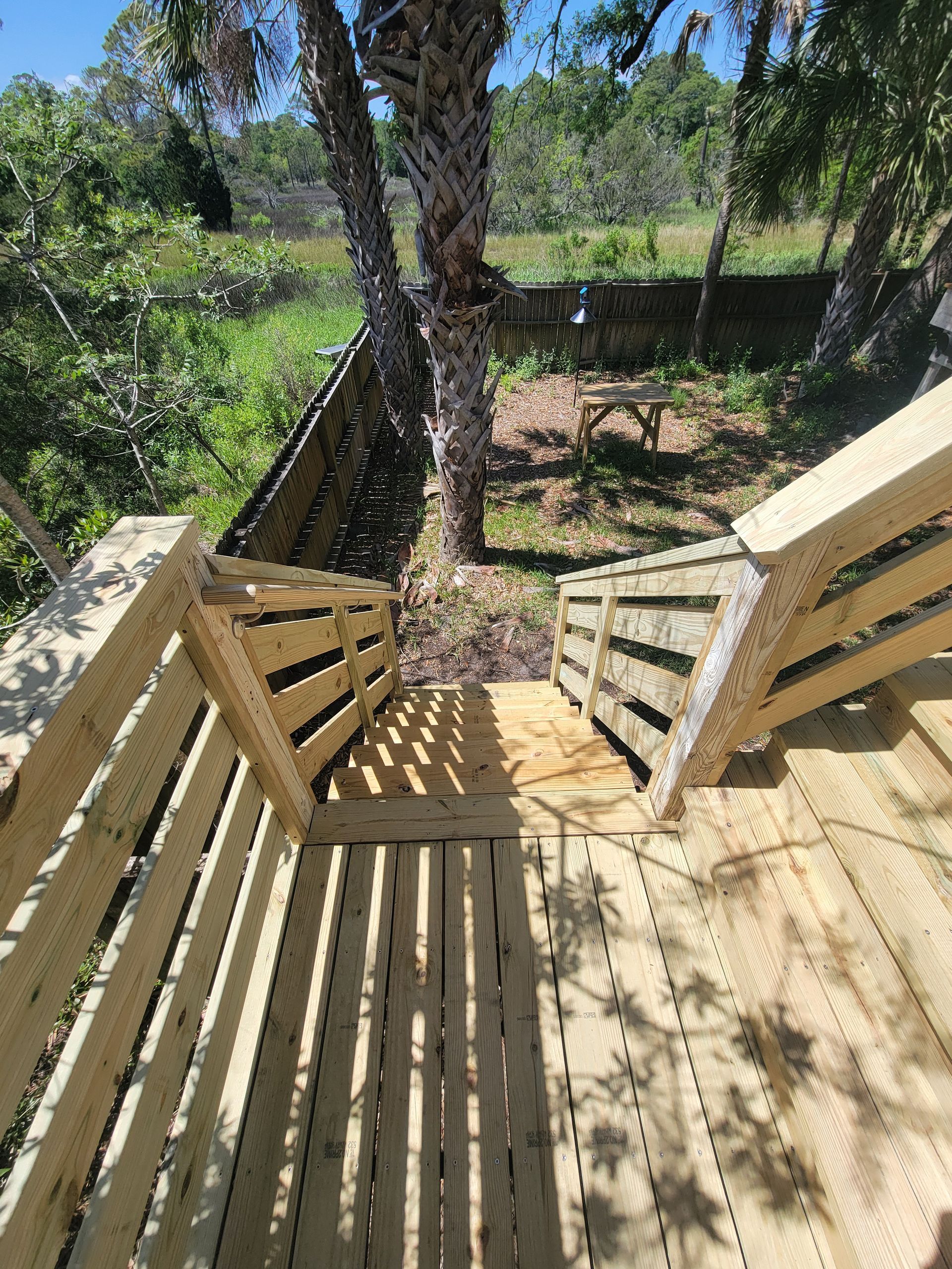 A wooden deck with stairs leading up to a tree.