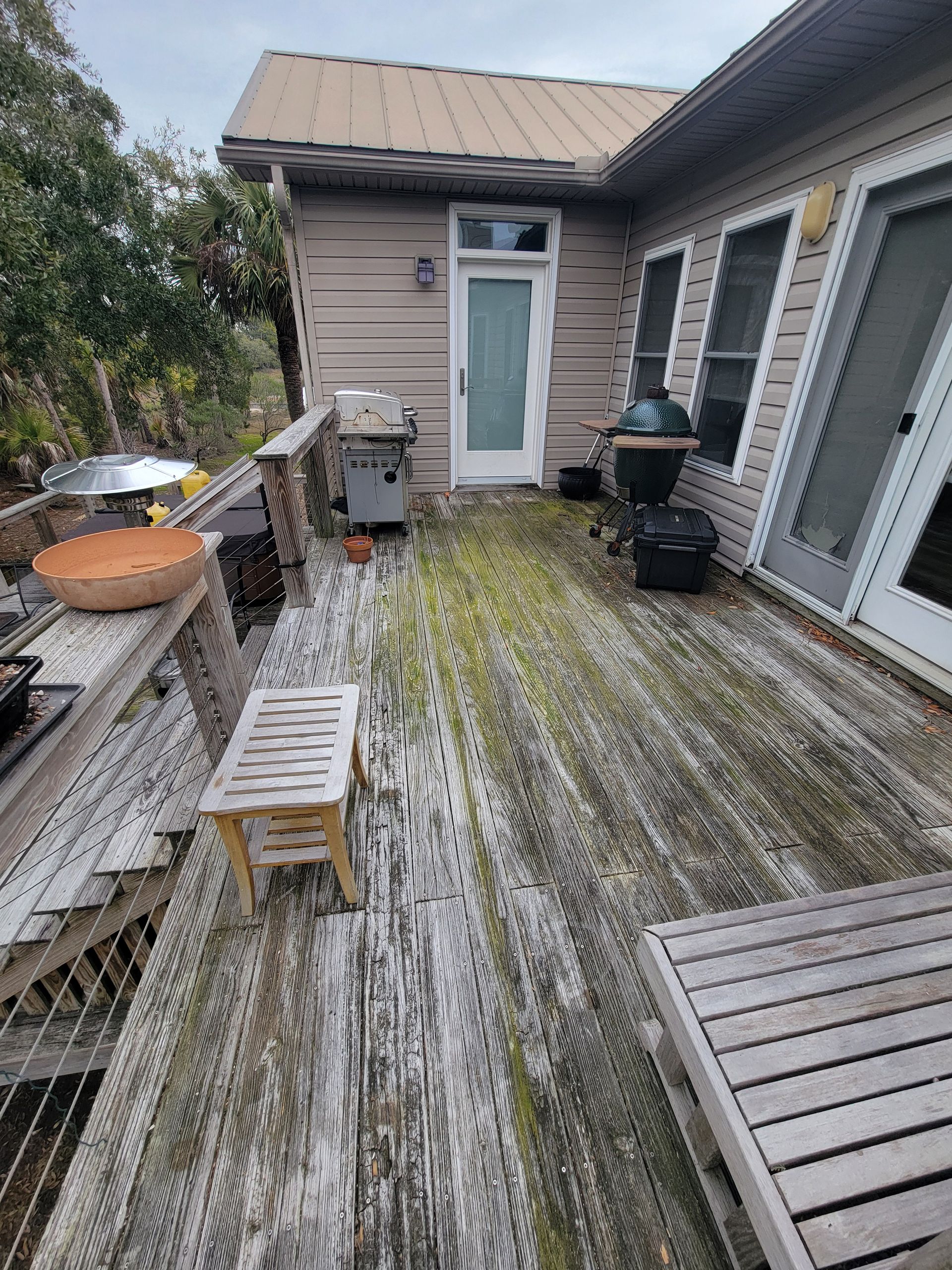 A wooden deck with a table and chairs on it in front of a house.