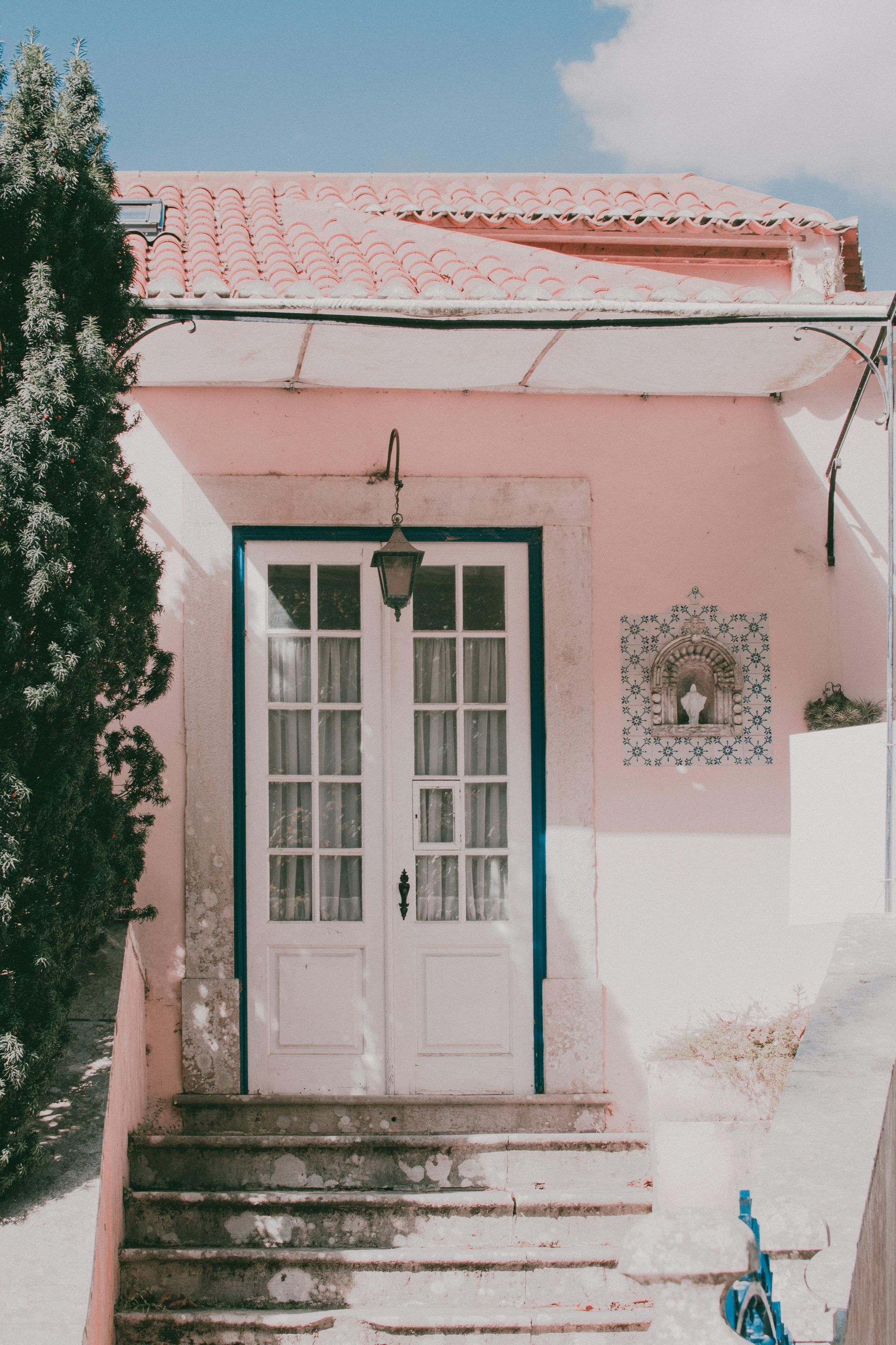 A pink house with a white door and stairs