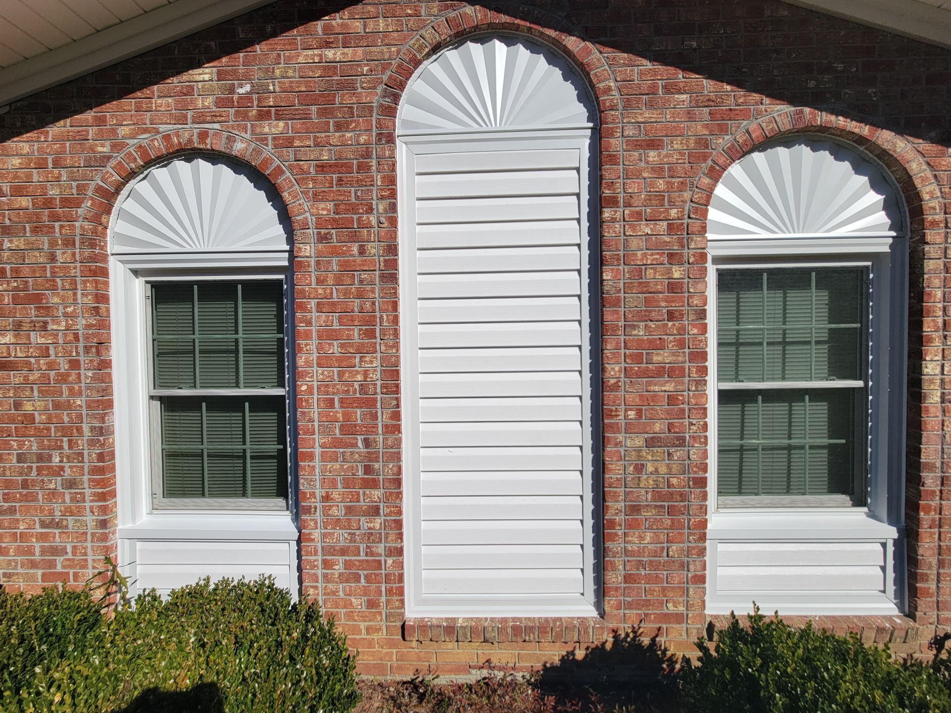 A brick house with arched windows and white shutters